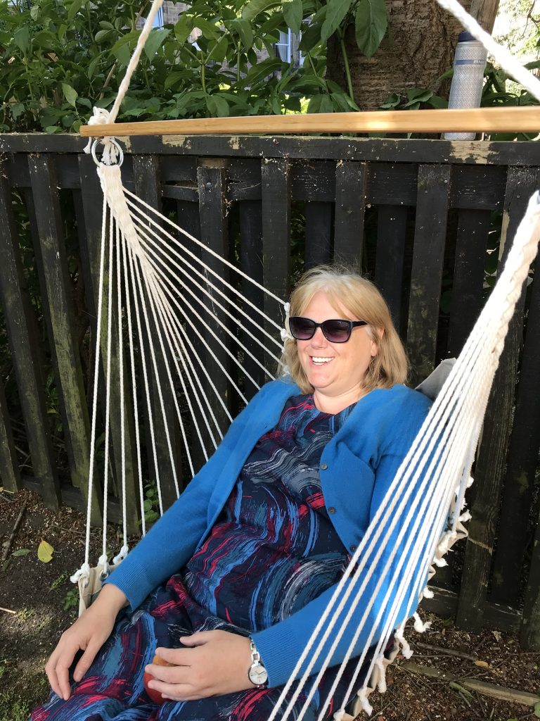 Lesley sitting in a swinging tree chair.