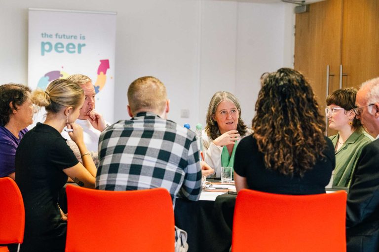 Minister for Mental Wellbeing, Maree Todd speaks with a group of Peer Supporters at a round table.