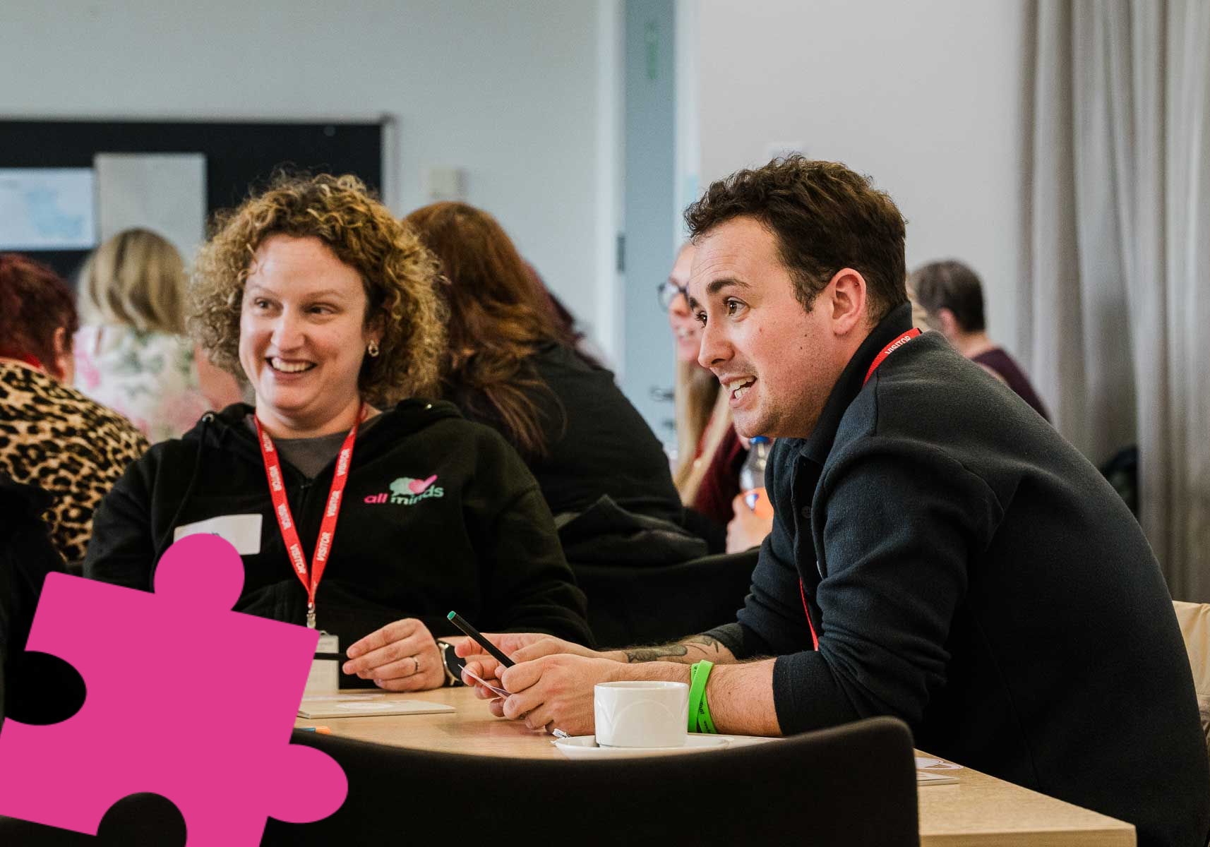Two event participants sitting at a table smiling.