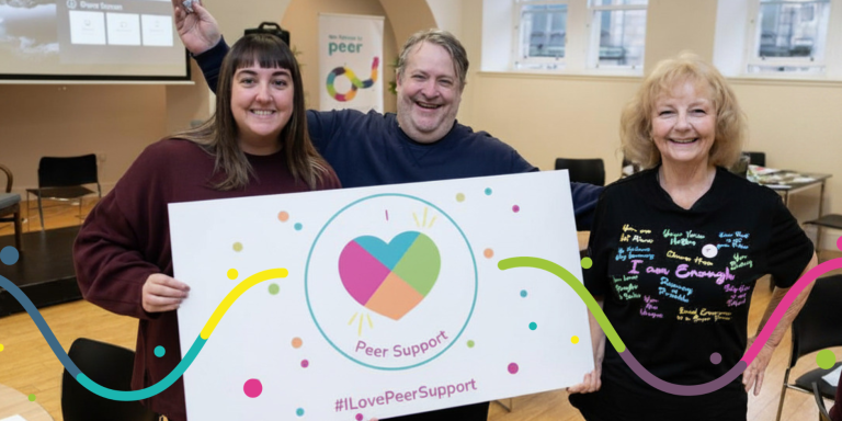 Three event participants holding a social media board saying #ILovePeerSupport.