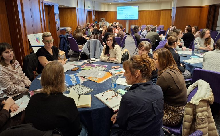 A photograph of people sitting around tables at an event.